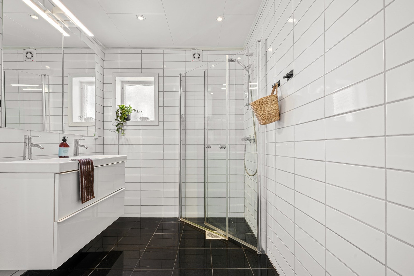 Badet inneholder: Foldedører i dusj, veggtoalett og baderomsinnredning med heldekkende servant samt belyst speil Galleribilde