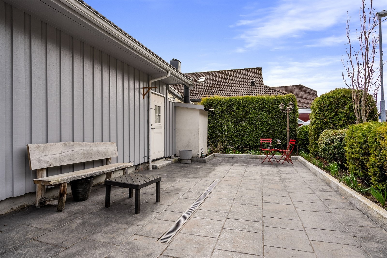 En steinbelagt uteplass på siden av huset gir flere soner for utendørs opphold. Galleribilde
