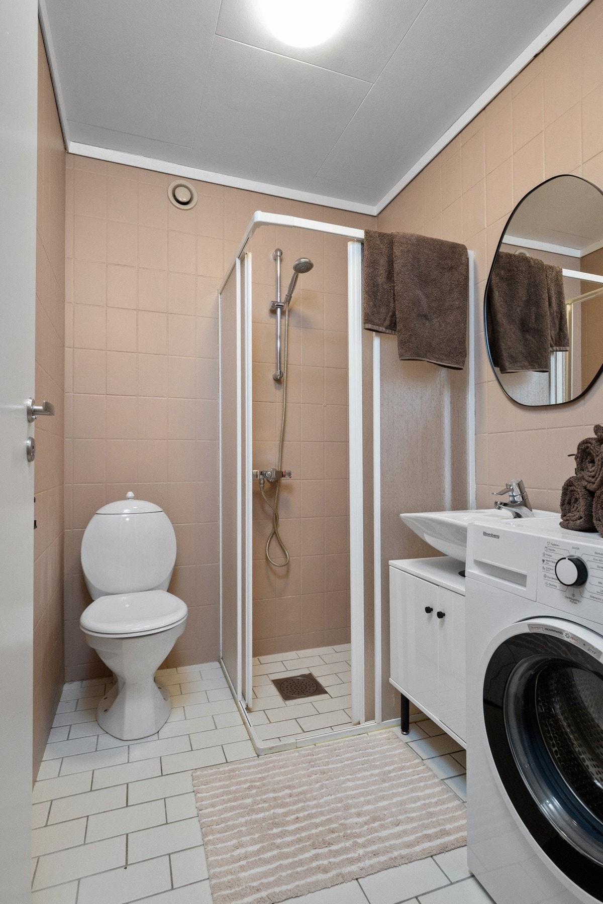 Badet er flislagt og inneholder servant, toalett, dusjløsning samt opplegg for vaskemaskin. Det er varmekabler i gulvet som gir en komfortabel løsning i hverdagen. Galleribilde