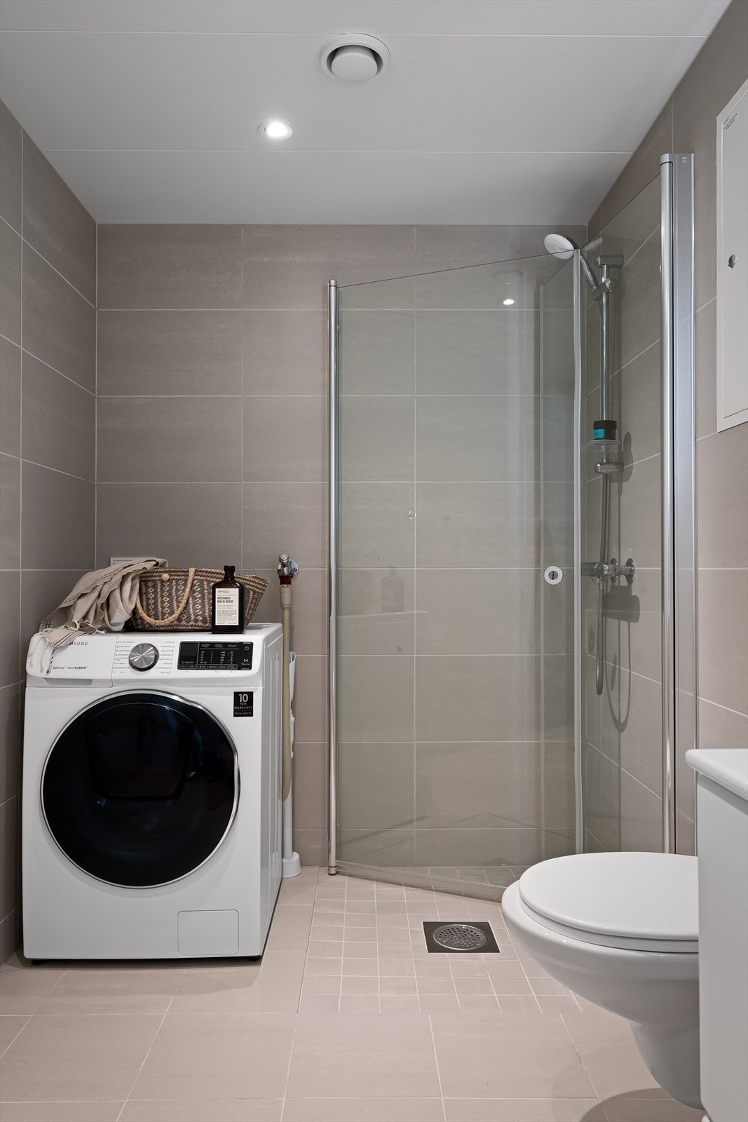 Badet er utstyrt med vegghengt toalett, dusjhjørne med svingbare glassdører og opplegg for vaskemaskin. Galleribilde