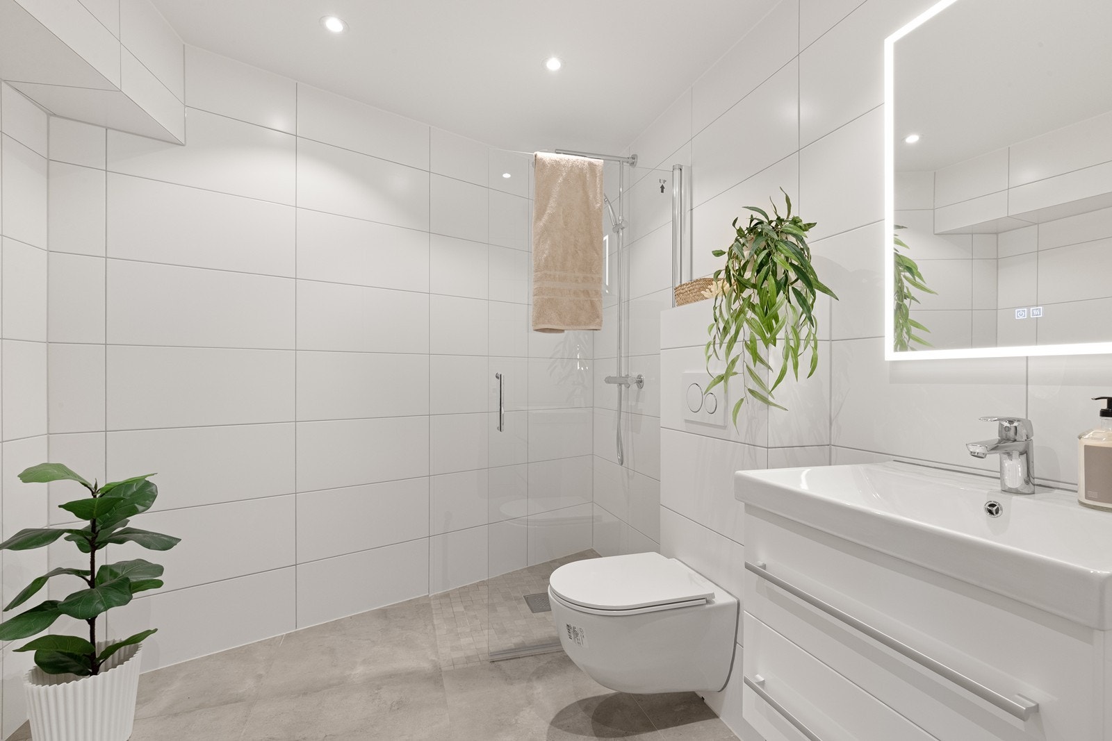 Lekkert flislagt bad med dusjnisje og glassvegg, servantinnredning og vegghengt wc. Downlights LED og uttak til vaskemaskin/tørketrommel. Galleribilde