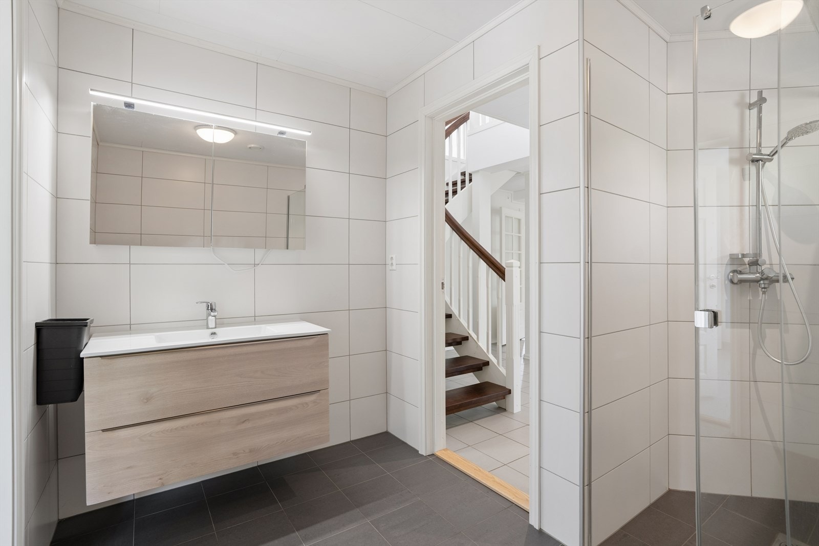 Badet i første etasje ble bygget nytt i 2023 med fliser, vegghengt toalett og innfellbare dusjvegger i glass. Galleribilde