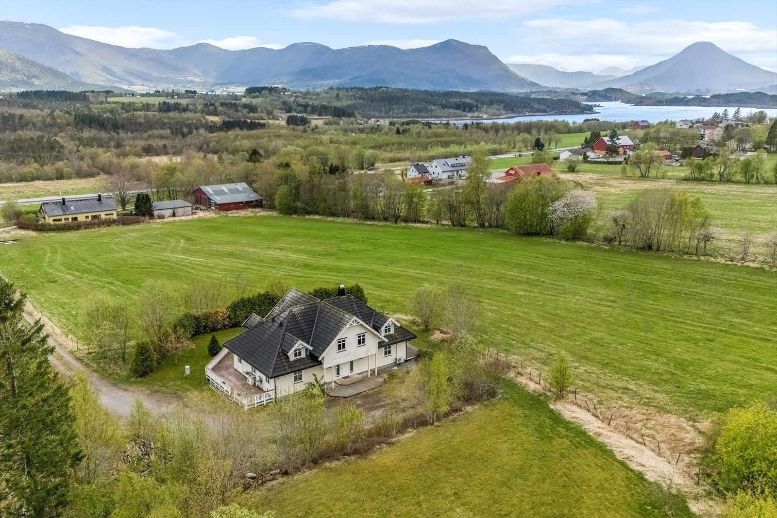 Eiendommen ligger i et landlig og åpent landskap med utsikt mot fjell og fjord. Galleribilde