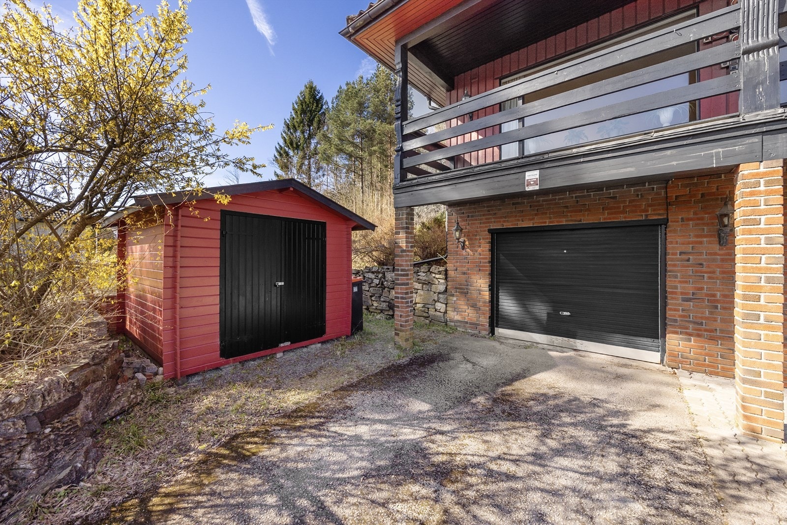 Integrert garasje med vippeport og portåpner, samt en frittstående hagebod for ekstra lagring. Galleribilde