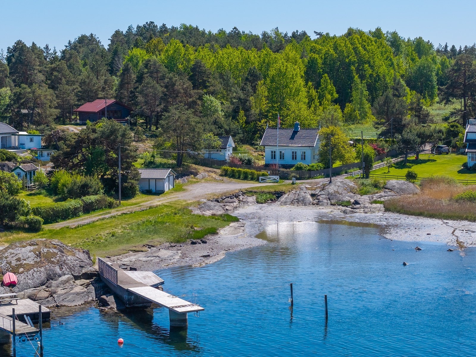 Huset med annekset sett fra bryggen som har badetrapp og båtplasser Galleribilde