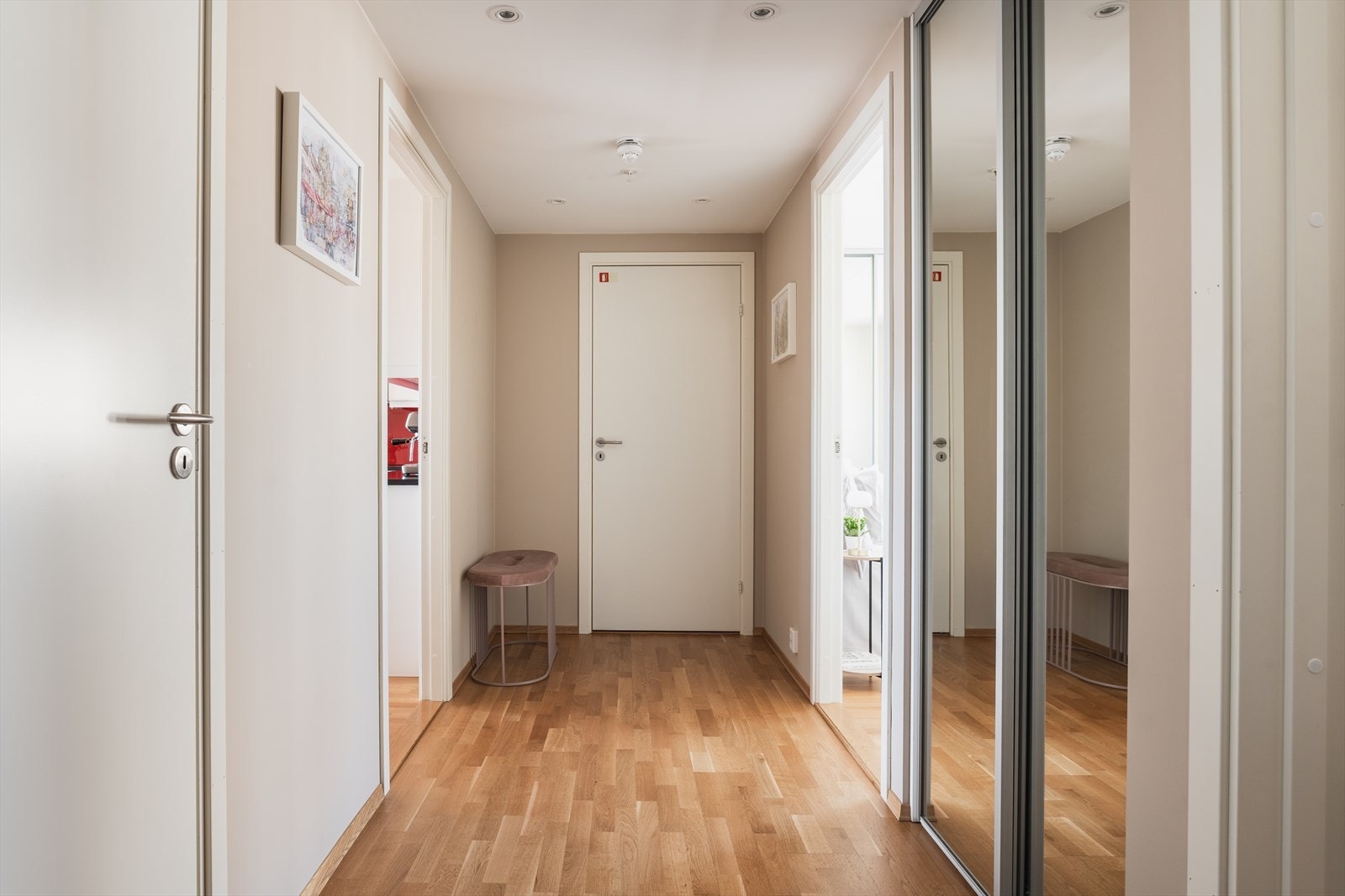 Innbydende entré med parkettgulv som strekker seg gjennom hele leiligheten og gir et helhetlig og tidløst preg. Entréen byr på gode oppbevaringsmuligheter i en praktisk skyvedørsgarderobe. Galleribilde