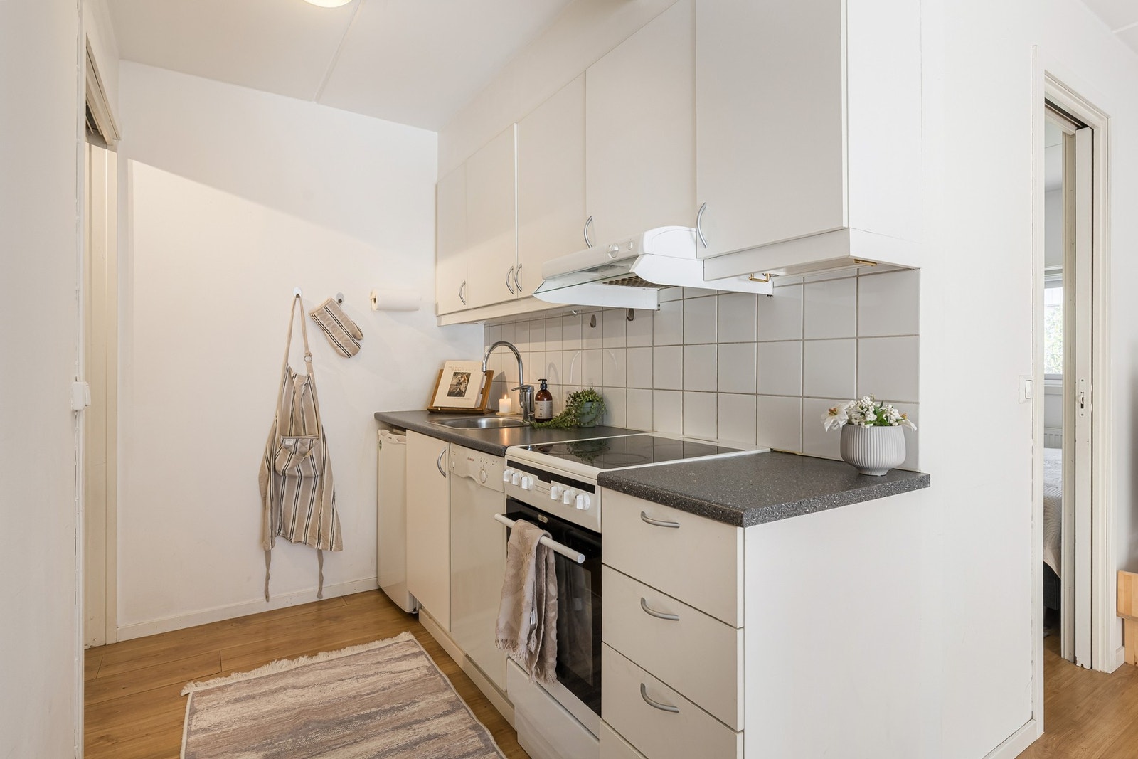 Kjøkken med hvite fronter og grå laminat benkeplate. Galleribilde
