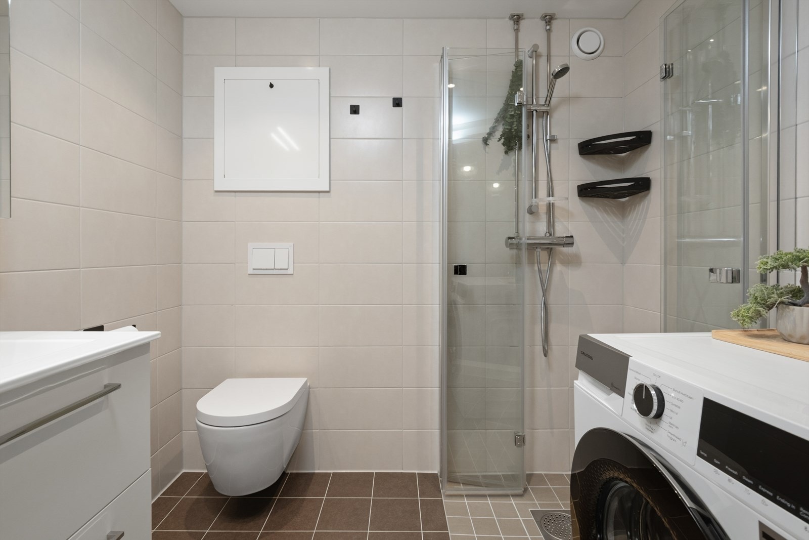 Badet er utstyrt med elektriske varmekabler, dusjvegger, vegghengt toalett, nedfelt servantinnredning og opplegg for vaskemaskin. Galleribilde