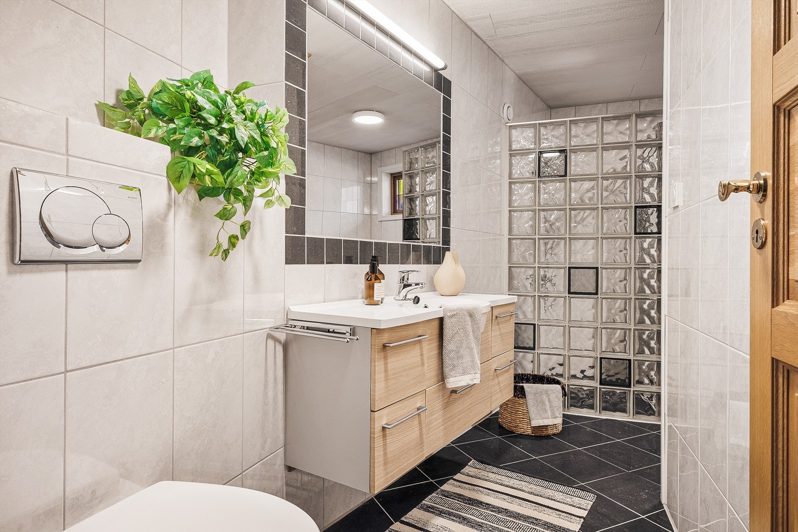 Dette badet har vegghengt toalett og servant med møblement. Gulvet har elektriske varmekabler. Galleribilde
