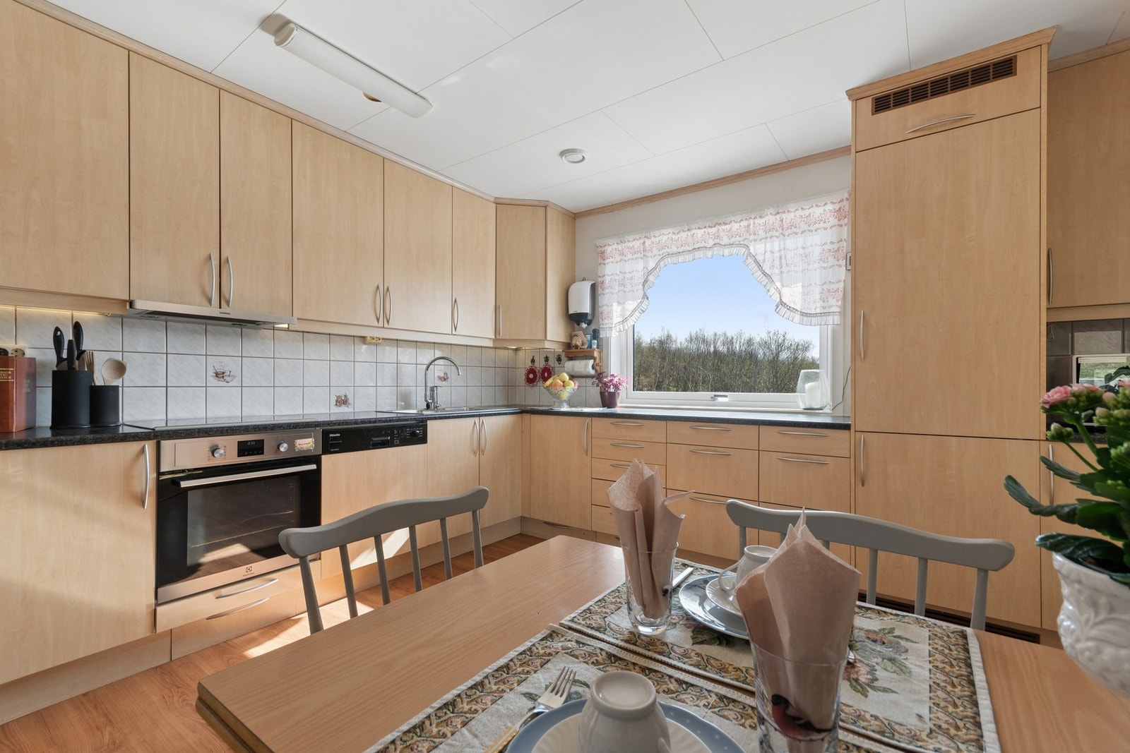 Kjøkkenet er utstyrt med integrert komfyr, koketopp, oppvaskmaskin og kjøl-/fryseskap. Det er også plass til en spiseplass ved vinduet. Galleribilde