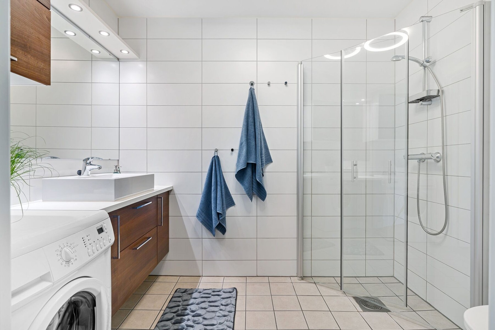 Pent og lyst flislagt bad med behagelig varme i gulv, innredning med rikelig av oppbevaringsplass og opplegg for vaskemaskin. Galleribilde