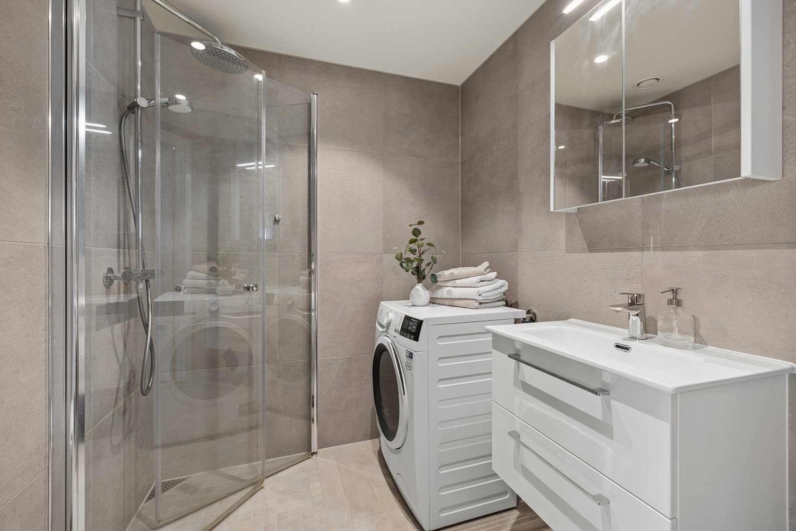 Badet er bygd som våtromskabin med fliser på vegg og opplegg for vaskemaskin. Galleribilde