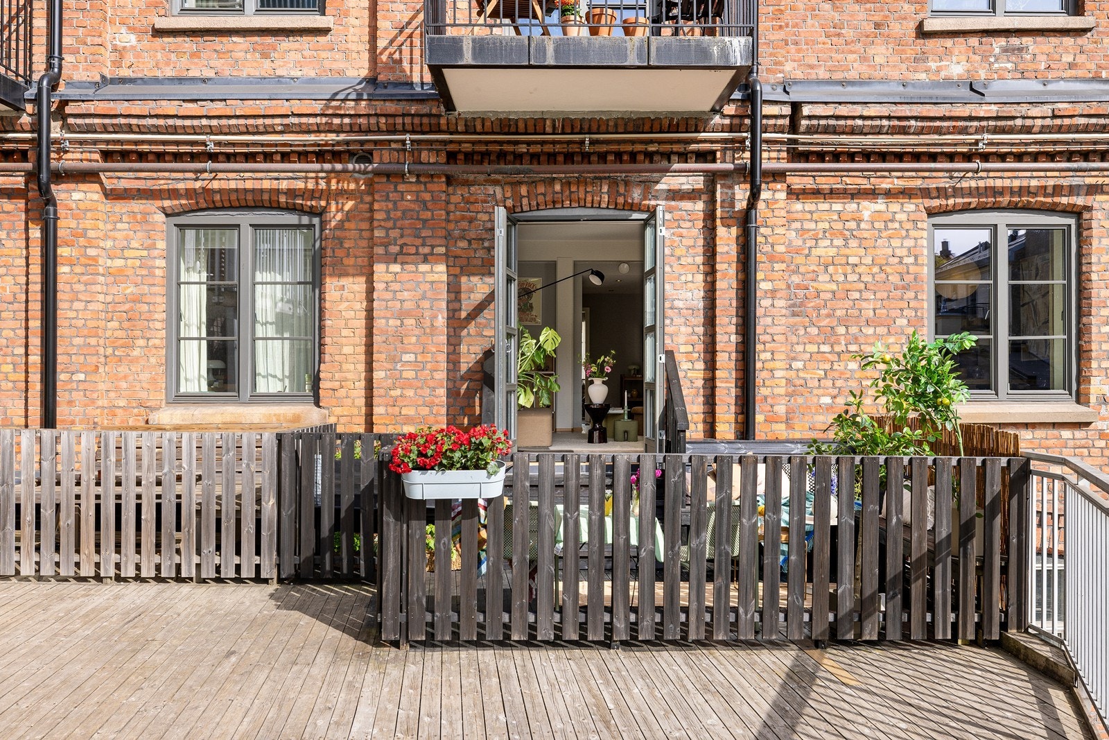 Fasade mot boligens uteplass med tegl, tredekke og inngjerdet privat terrasseareal Galleribilde