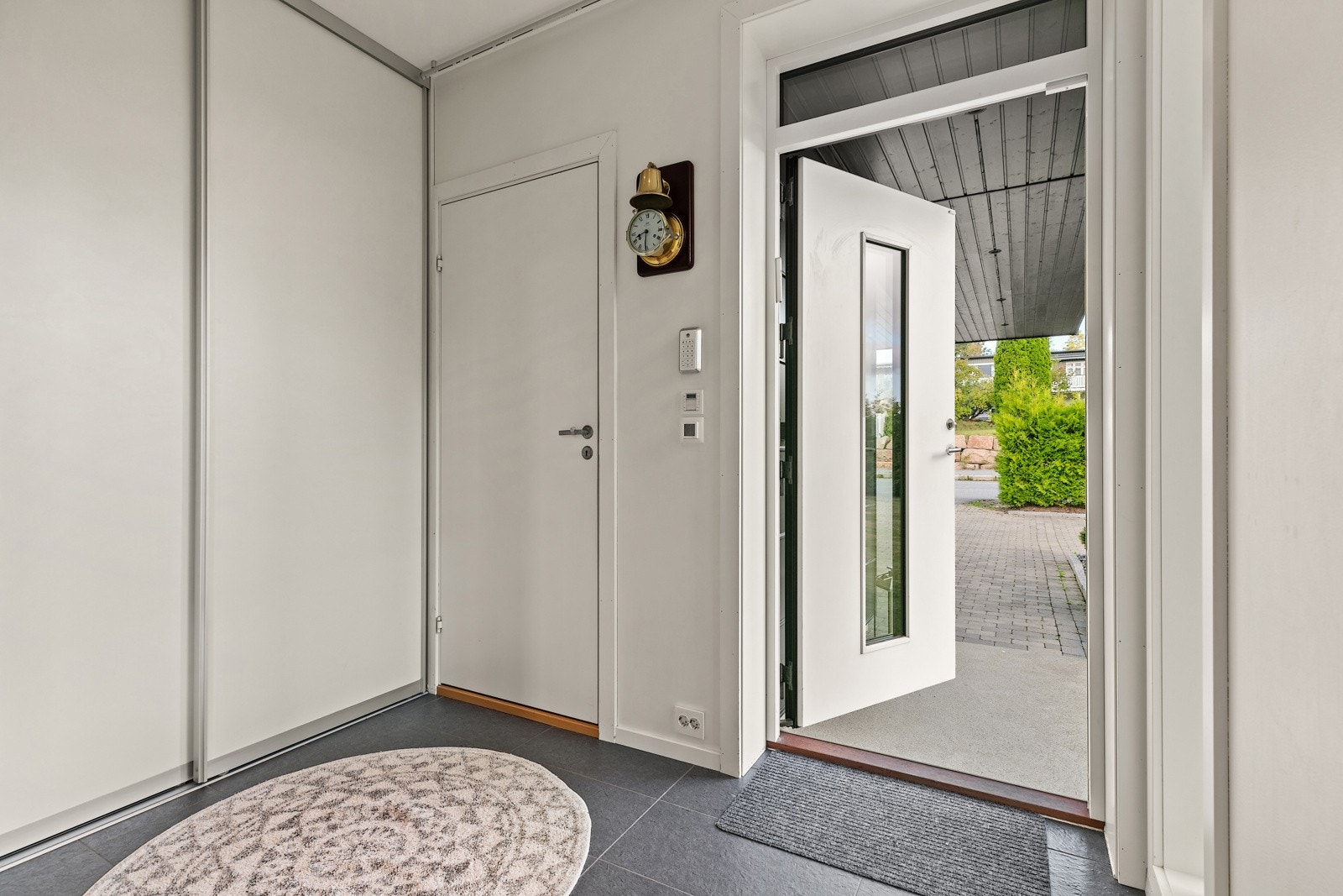 Entré med integrerte garderobeskap, fliselagt gulv og ytterdør med glassfelt. Galleribilde