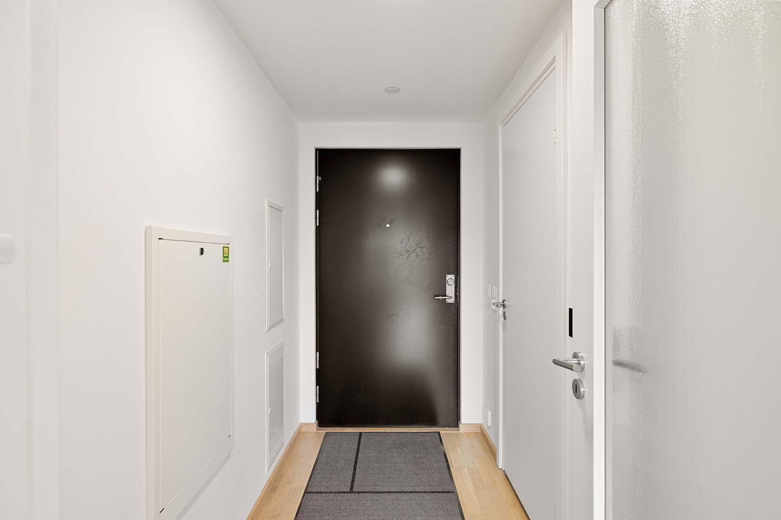 Entréen gir et lyst og moderne førsteinntrykk med hvitmalte flater og en lys, tidløst eikeparkett. Galleribilde