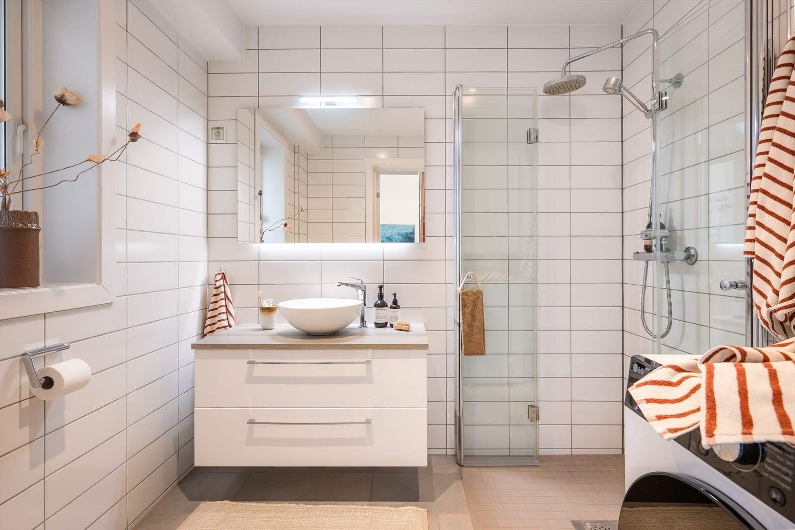 Lys flislagt bad fra 2007. Badet har varmekabler i gulv, servant med innredning, klosett, vaskemaskin og dusjhjørne. Galleribilde
