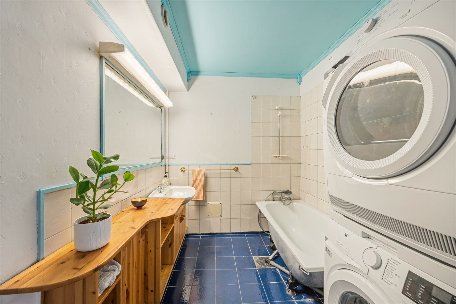 Stort baderom bestående av innredning med servant, toalett, dusjnisje med badekar og opplegg for vaskemaskin. I 2022 ble nye varmekabler installert med ny kurs. Galleribilde