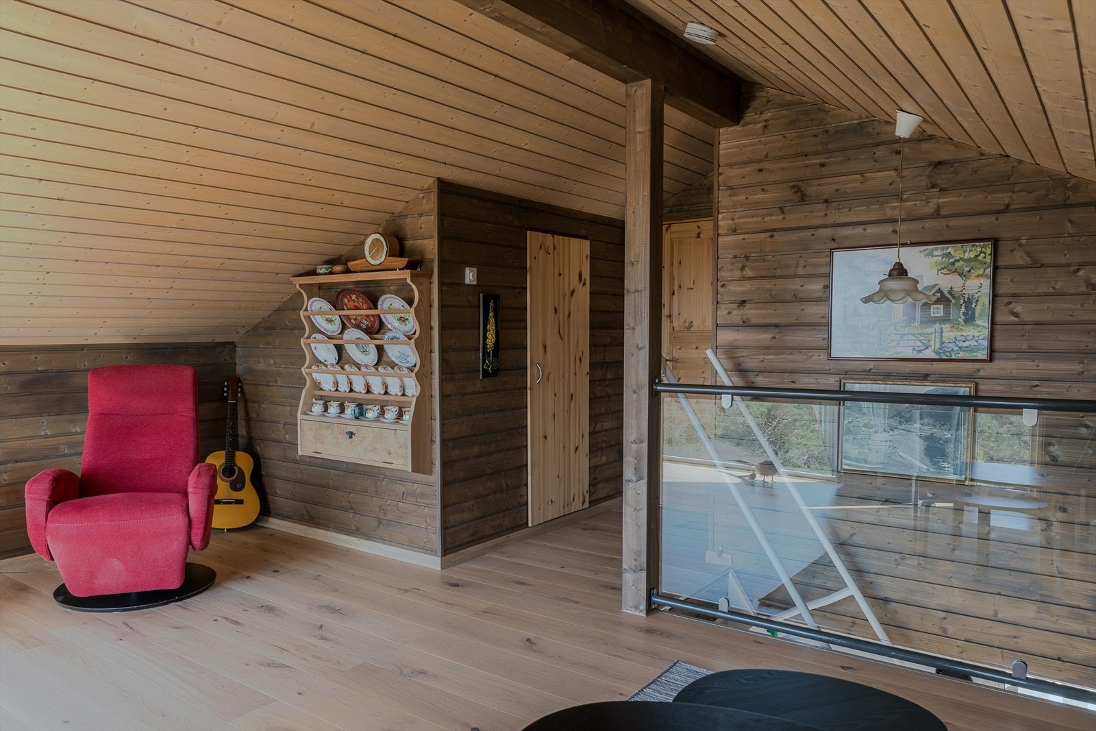 Sjarmerende loftsrom med rustikk trepanel, skrå himling og åpen løsning - en rolig og innbydende sone med god romfølelse og hyggelig utsyn. Galleribilde