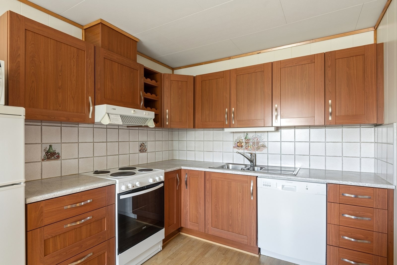 Kjøkkeninnredningen er fra byggeår og har brune, profilerte fronter samt lys laminert benkeplate med nedfelt oppvaskkum i stål. Galleribilde