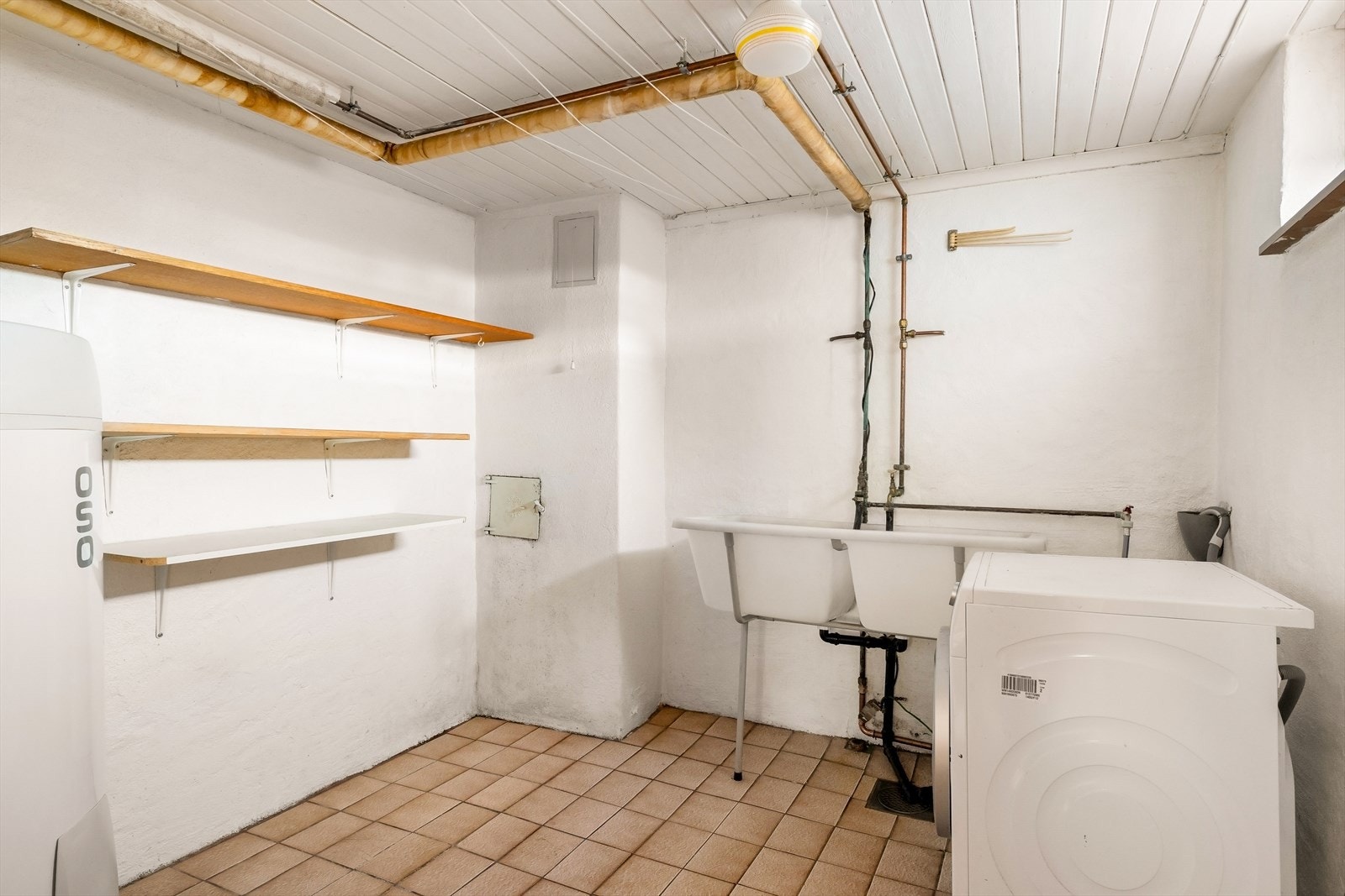 Praktisk vaskerom i første etasje med flislagt gulv og opplegg for vaskemaskin. Galleribilde