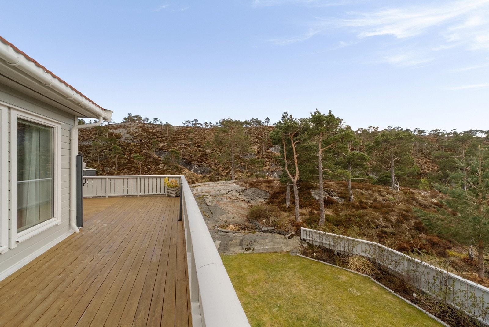Verandaen strekker seg rundt hjørnet på huset, og man har utsikt sørover mot Lauvhaugen. Galleribilde