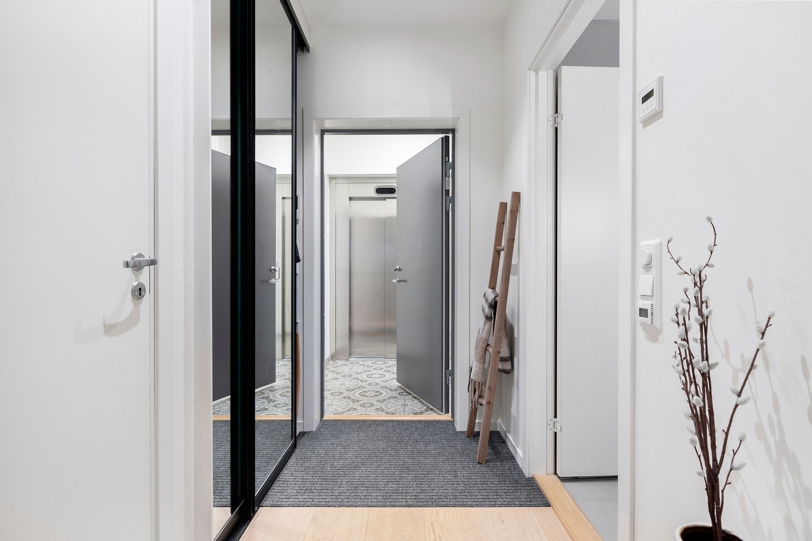Romslig entre med stor skyvedørsgarderobe med speilfronter. Dørcalling. Galleribilde