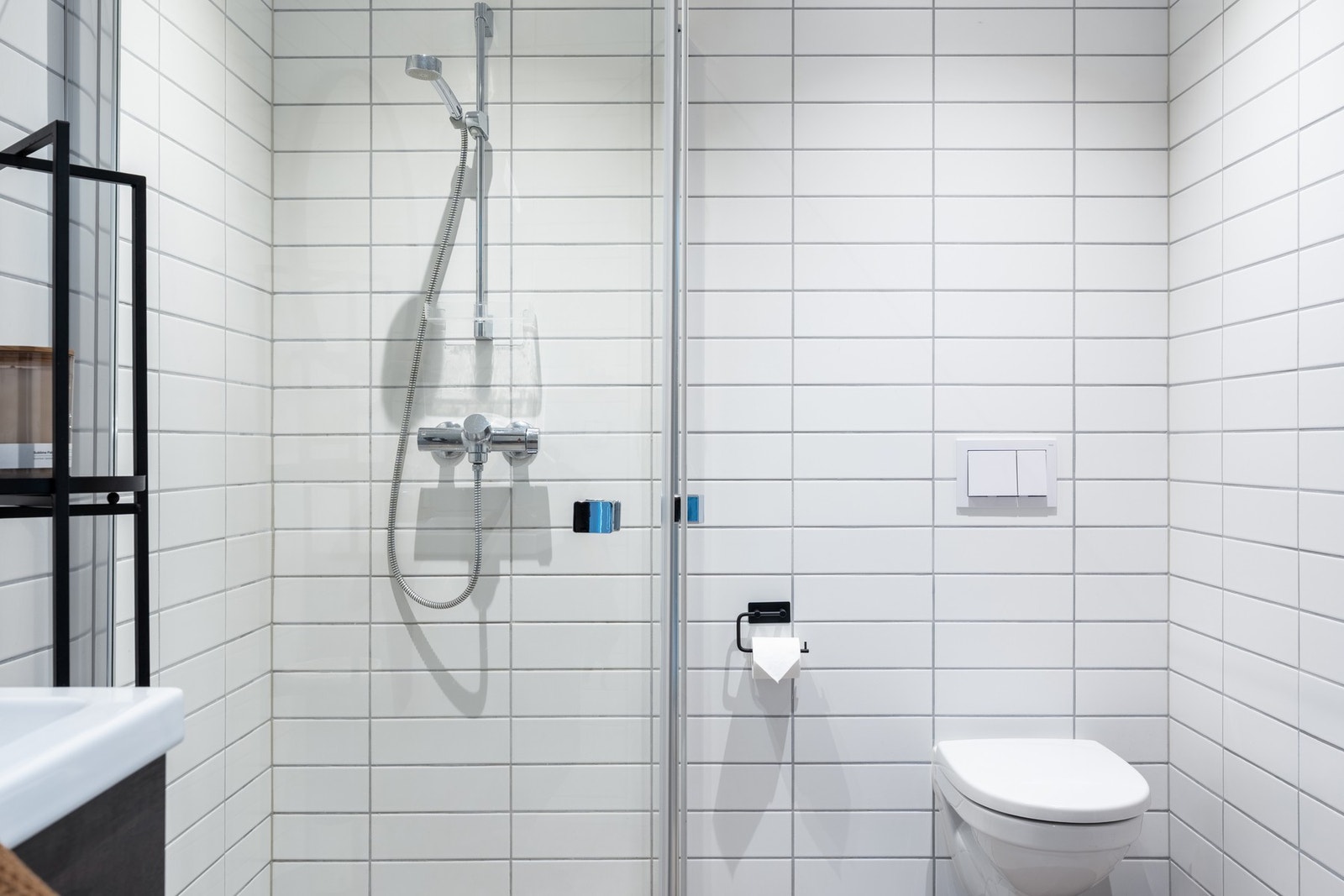Badet er innredet med vegghengt toalett, dusjhjørne med glassvegger, og et moderne baderomsmøblement med speil og belysning. Galleribilde