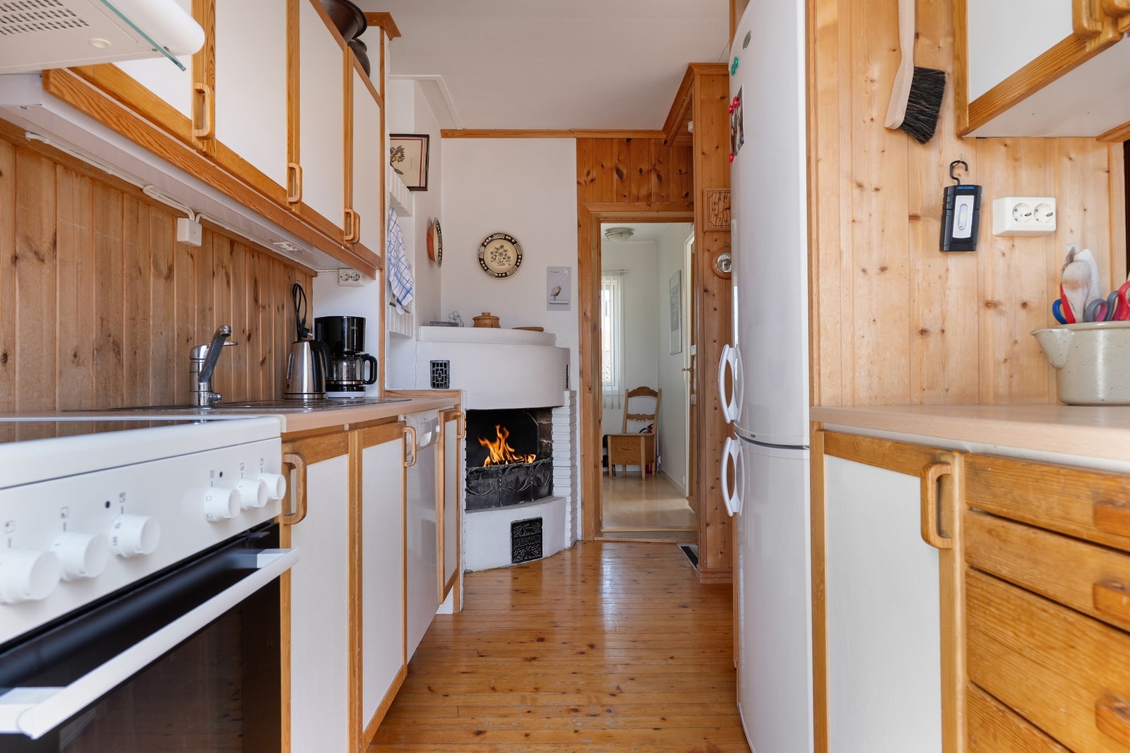 Kjøkkeninnredning med profilerte furu fronter og benkeplater i heltre. Frittstående komfyr (medfølger ikke), oppvaskmaskin og kjøleskap med frysedel. Galleribilde