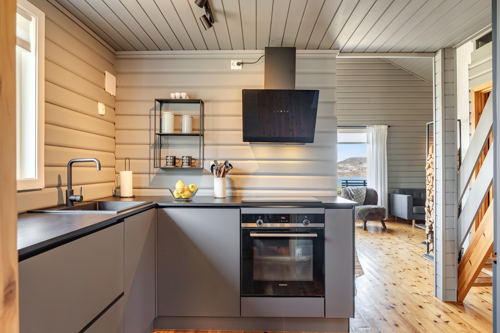 Pent, moderne kjøkken i åpen løsning mot stue. Kjøkkenet er utstyrt med frittstående kjøl-/fryseskap samt integrert platetopp og stekeovn, som medfølger i handelen. Galleribilde