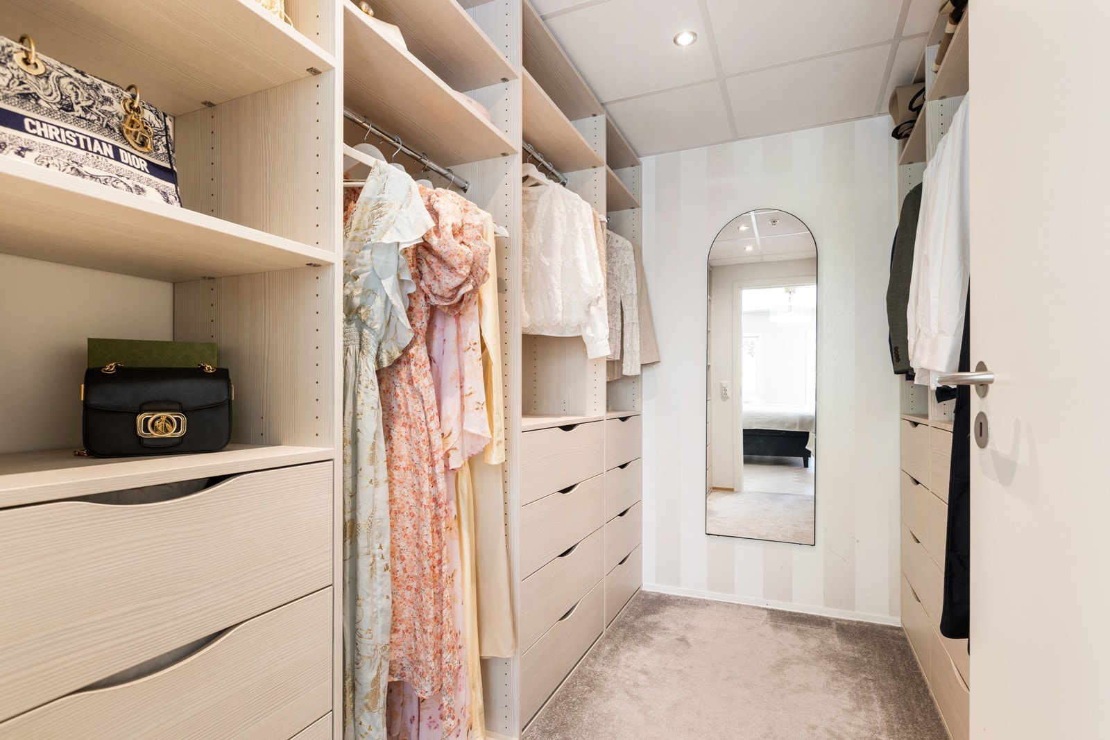 Innredet walk-in garderobe med teppe på gulvet i tilknytning til hovedsoverommet. Galleribilde