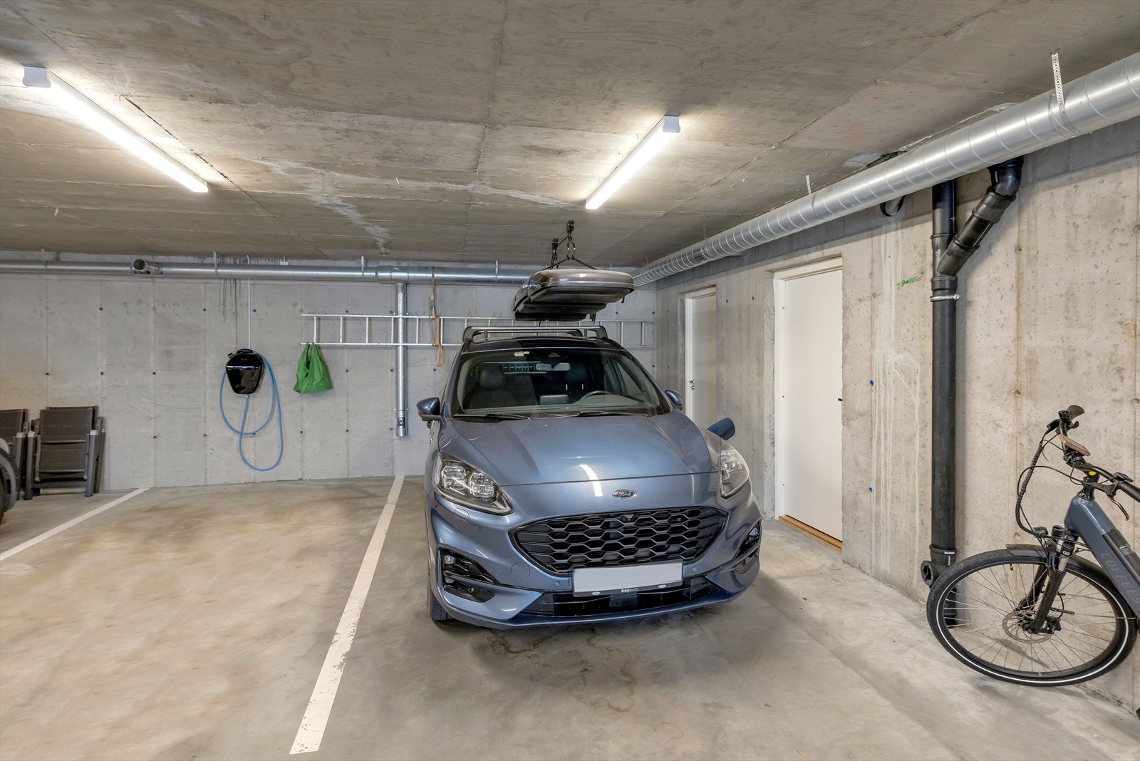 Parkeringsplass 1 med el lader. Bod innerst til høyre i bildet følger Galleribilde