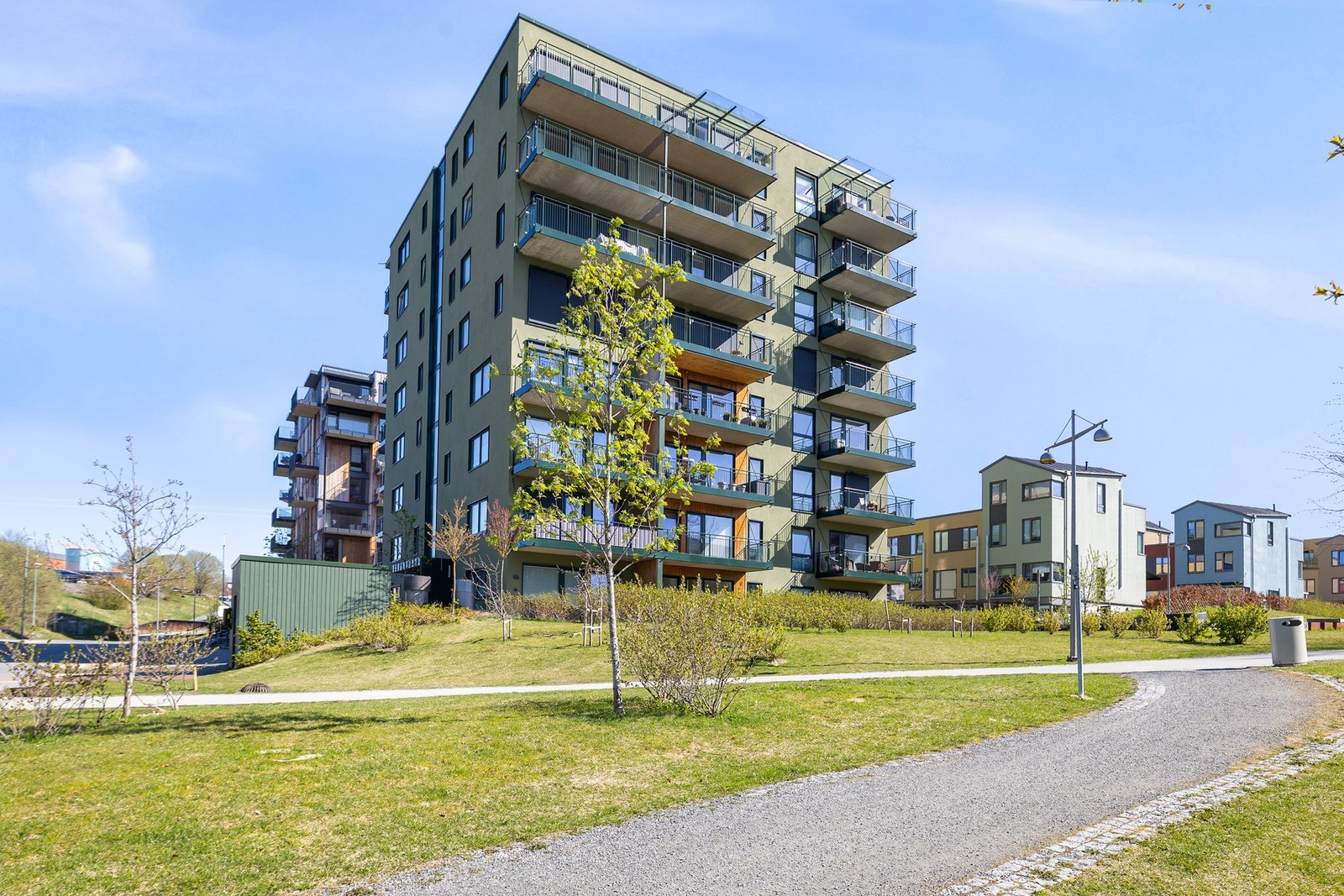 Fasadebilde. Pent og opparbeidet uteområde mellom blokkene. Oppleves frodig og grønt på sommerhalvåret. Galleribilde