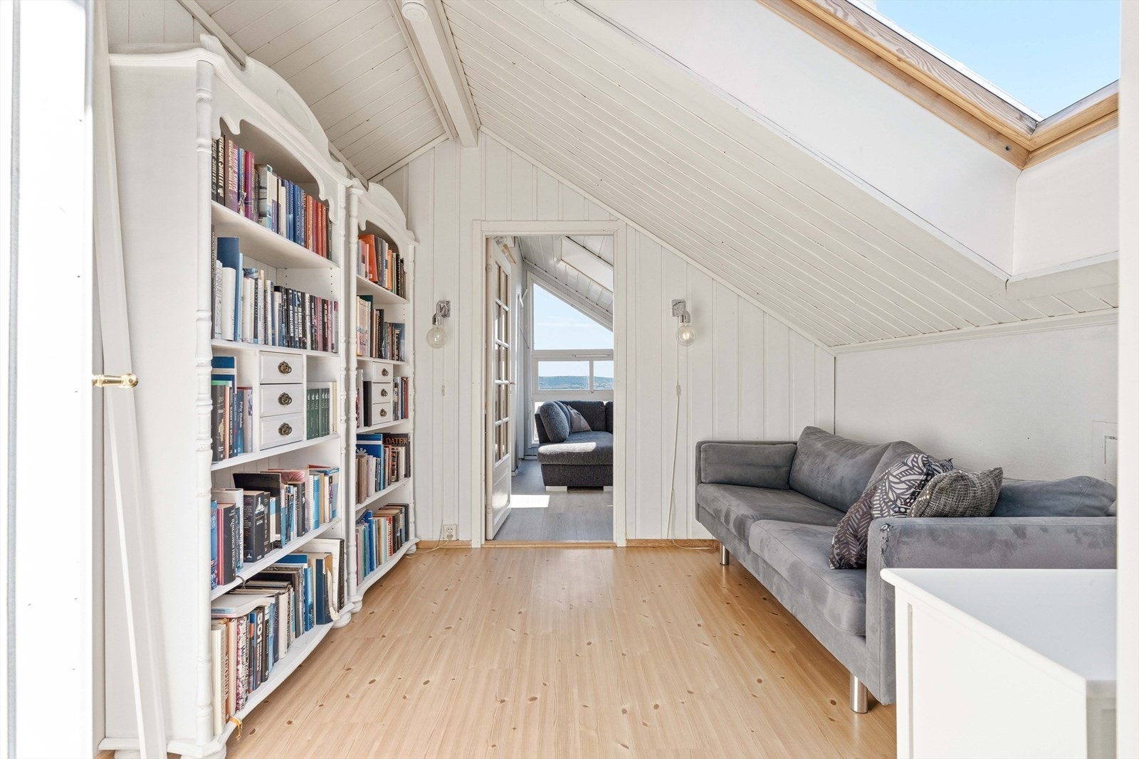 Opp trappen kommer man til gangen på loftet, innredet med sofa og bokhyller. Galleribilde