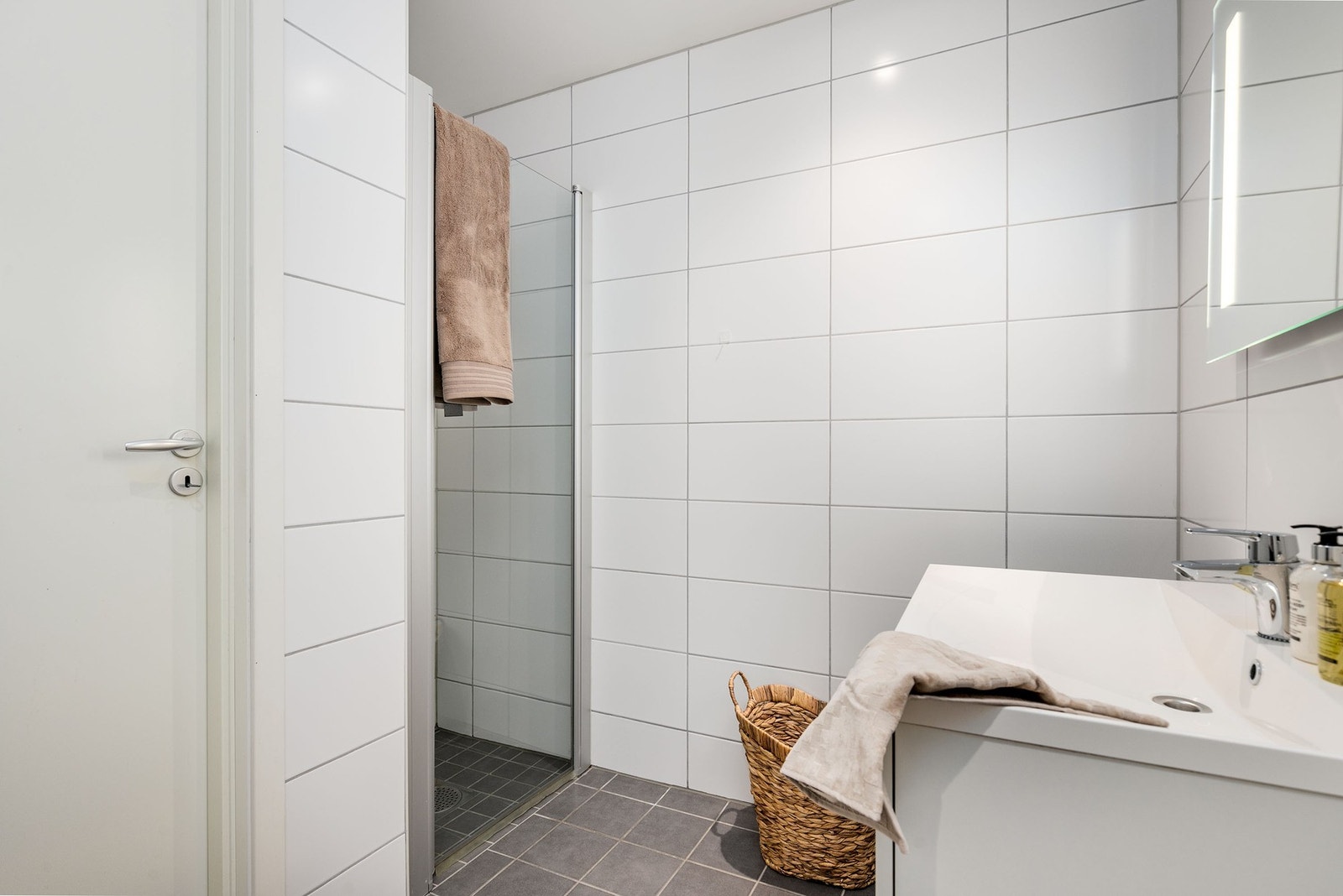Badet er utstyrt med servantmøblement, speil med integrert belysning, vegghengt toalett og dusjhjørne med innfellbare glassdører. Galleribilde
