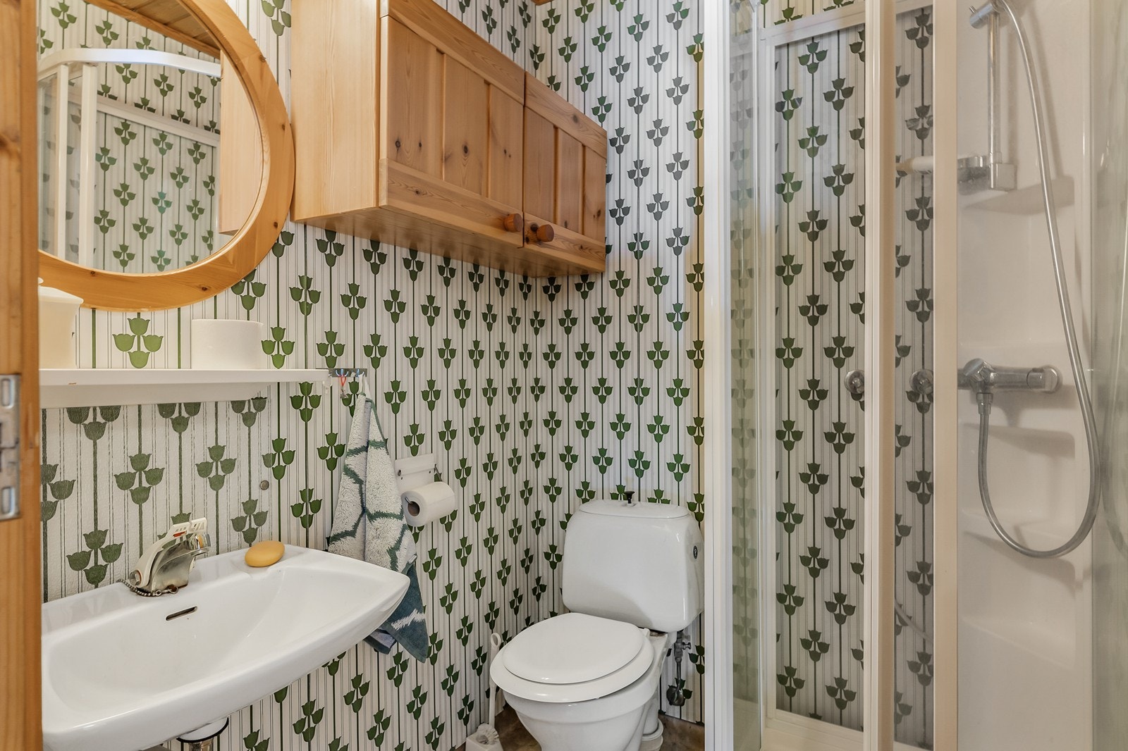 Badet er utstyrt med dusjkabinett, servant og toalett, men er fra byggeåret og har behov for oppgradering. Galleribilde