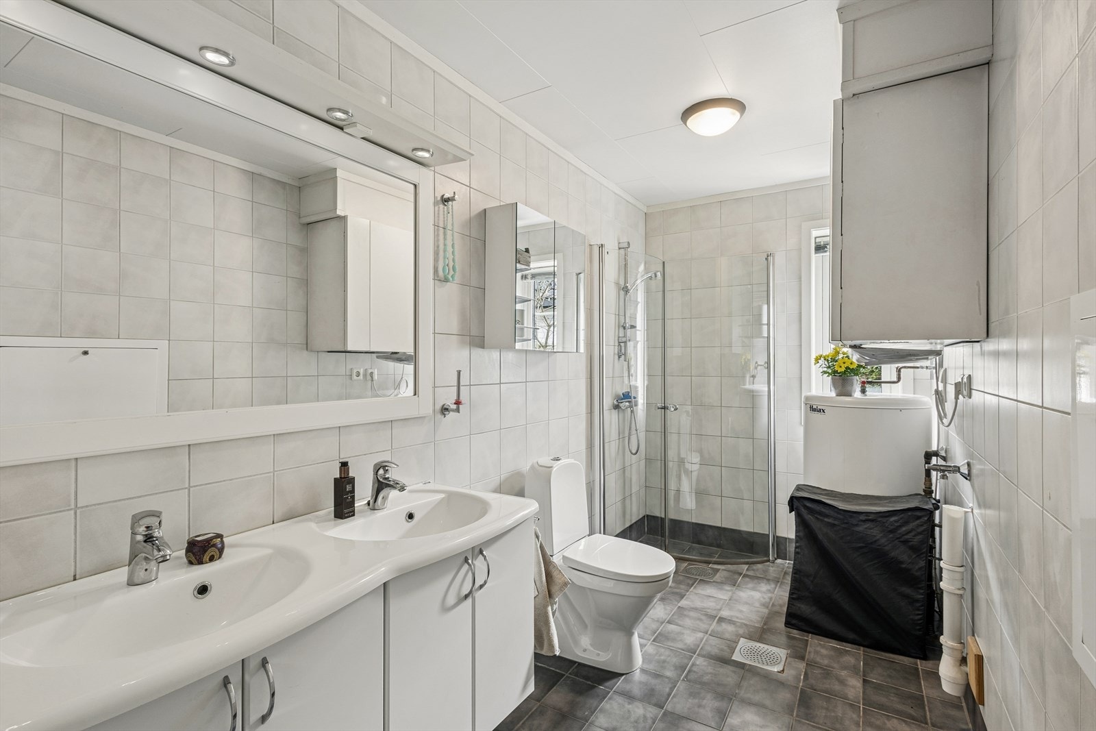 Badet er innredet med dobbelservant med underskap, speil, dusjdører og gulvmontert toalett. Det er også opplegg for vaskemaskin. Galleribilde