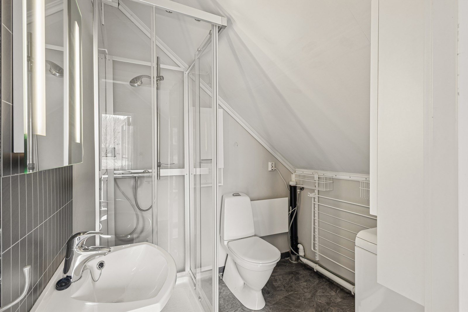 Badet i leiligheten har dusjkabinett, gulvbelegg og opplegg for vaskemaskin. Galleribilde