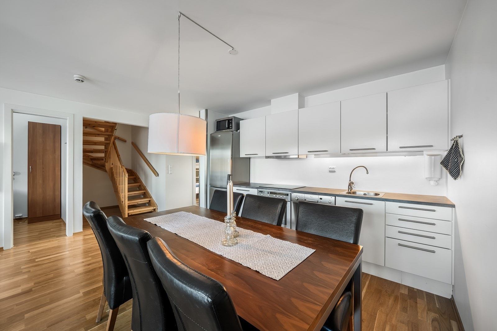 Tidløst hvitt kjøkken med glatte flater. Innredet med integrert komfyr og enkeltstående oppvaskmaskin og kombiskap. Galleribilde