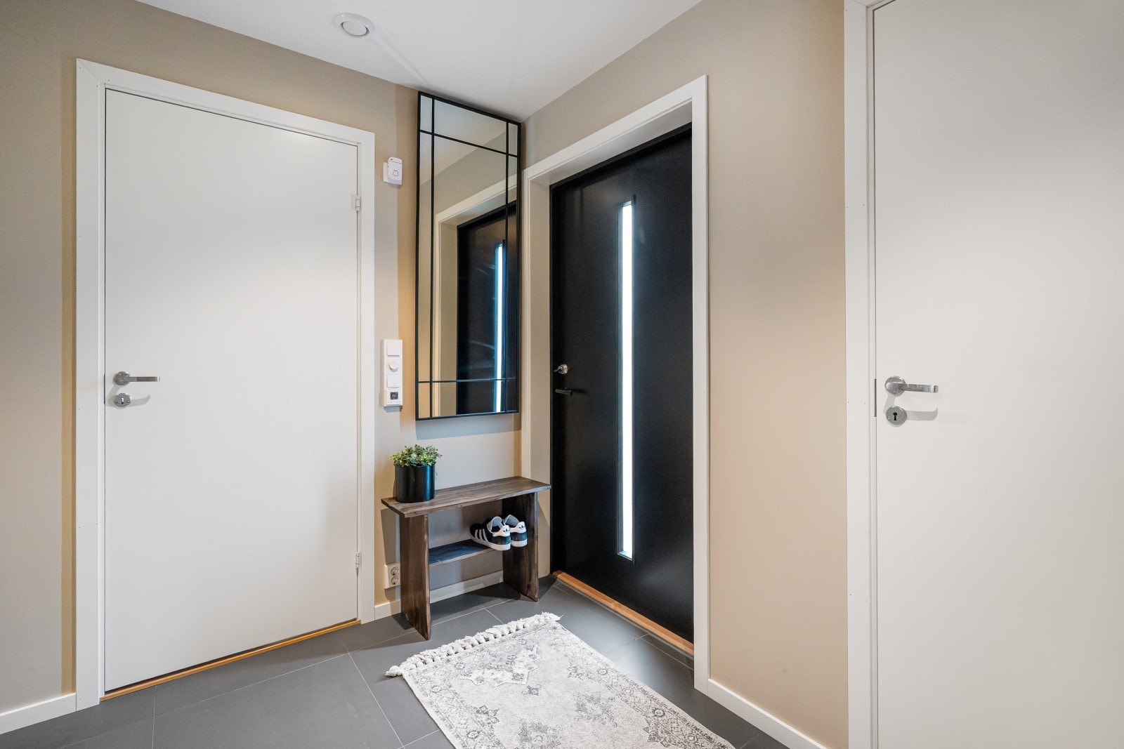 Inngangspartiet har en moderne, svartlakkert ytterdør med glassfelt. Galleribilde