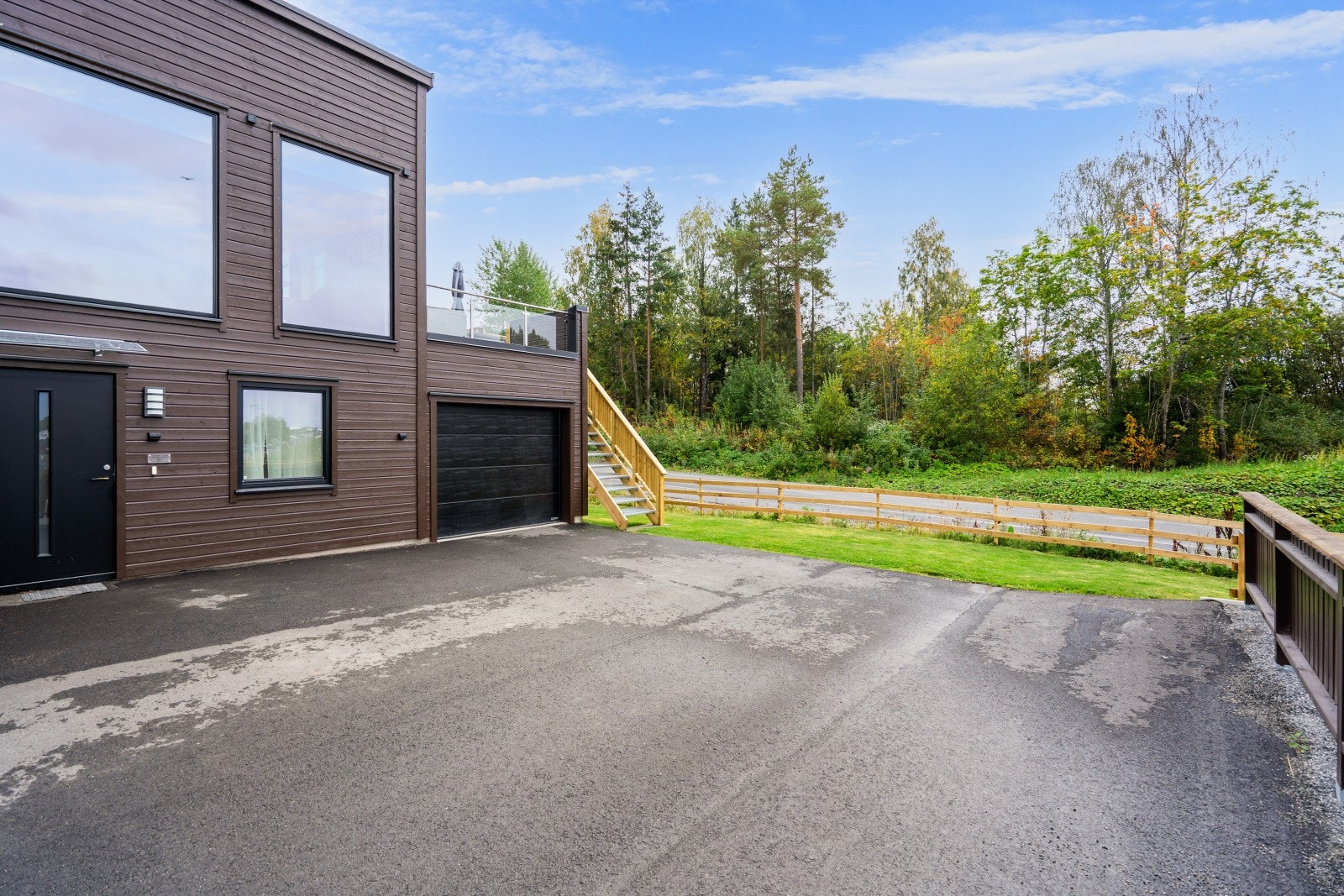 Asfaltert gårdsplass og integrert garasje med en praktisk bod i bakkant. Galleribilde