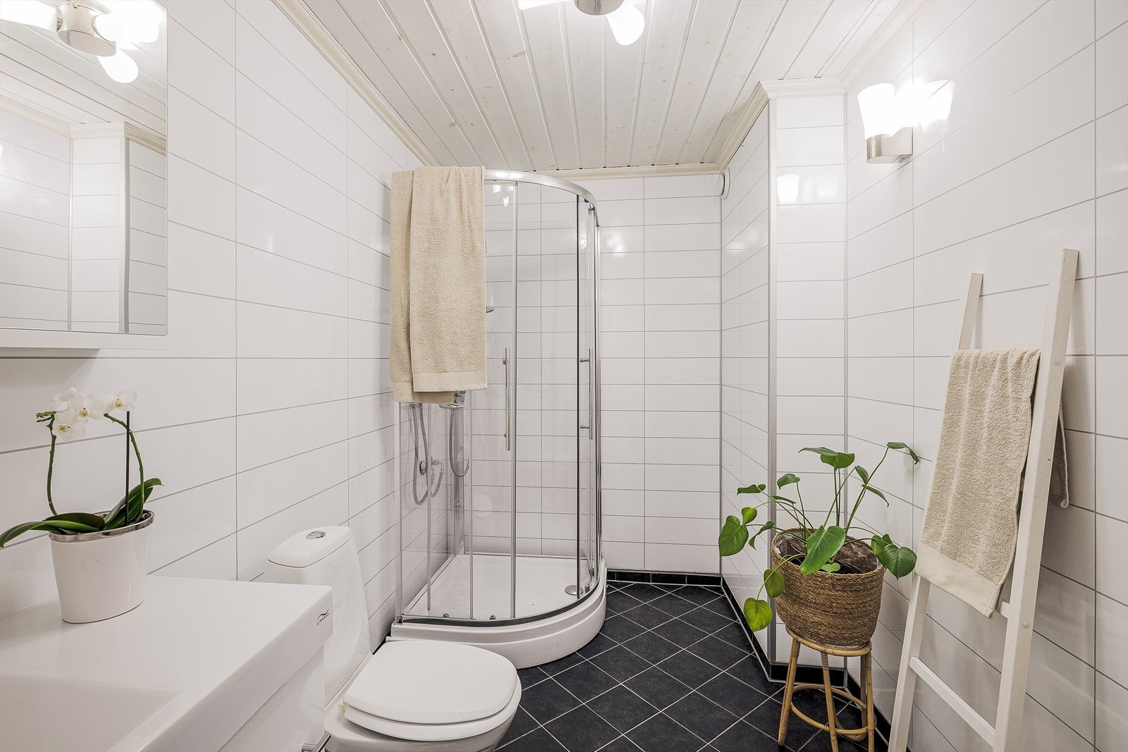 Badet er praktisk innredet med dusjkabinett, servant med skuffeseksjoner og vegghengt speil. Galleribilde