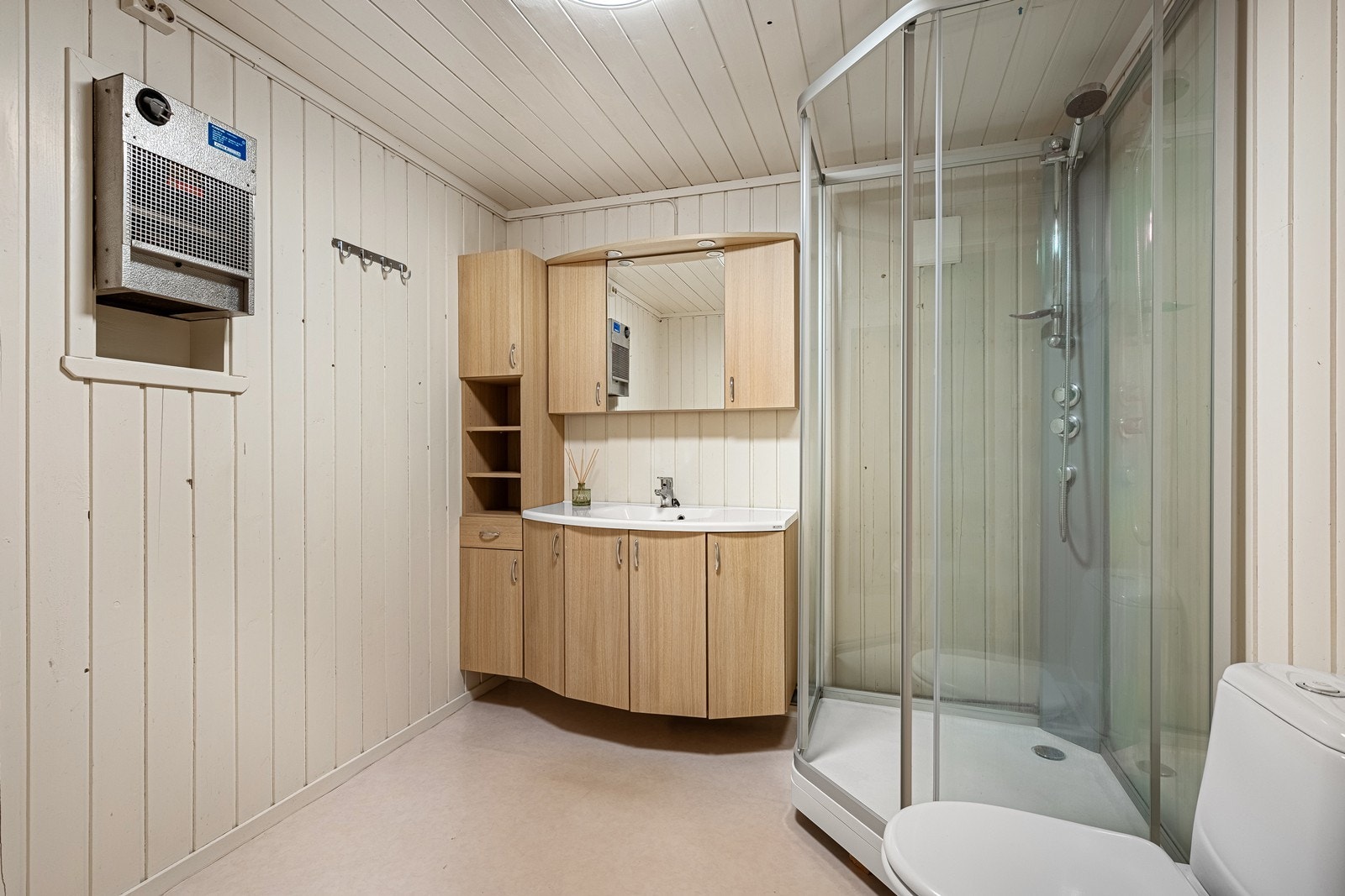 Bad med wc, dusjkabinett, håndvask med skap og speilskap. Galleribilde