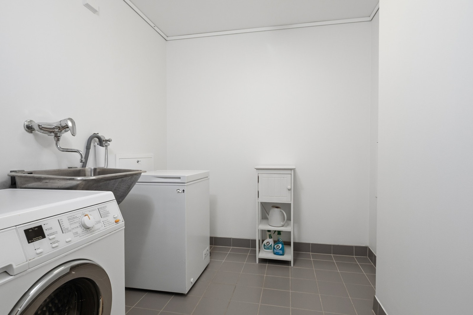 Leiligheten har eget vaskerom med flislagt gulv med varme og fall til sluk. Rommet er innredet med benk, skyllekar og opplegg for vaskemaskin, noe som gir en praktisk og funksjonell løsning for klesvask og oppbevaring. Galleribilde