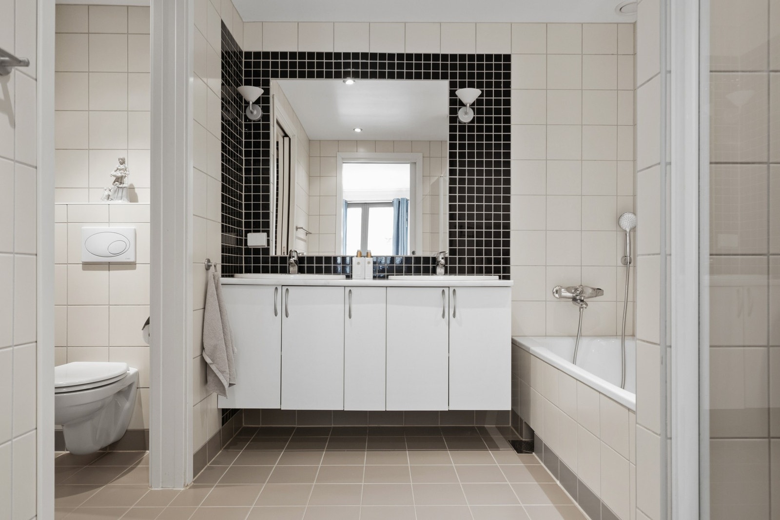 Badet er fra byggeår og har en praktisk utforming med flislagte overflater på vegger og gulv, samt varmekabler i gulvet. Galleribilde