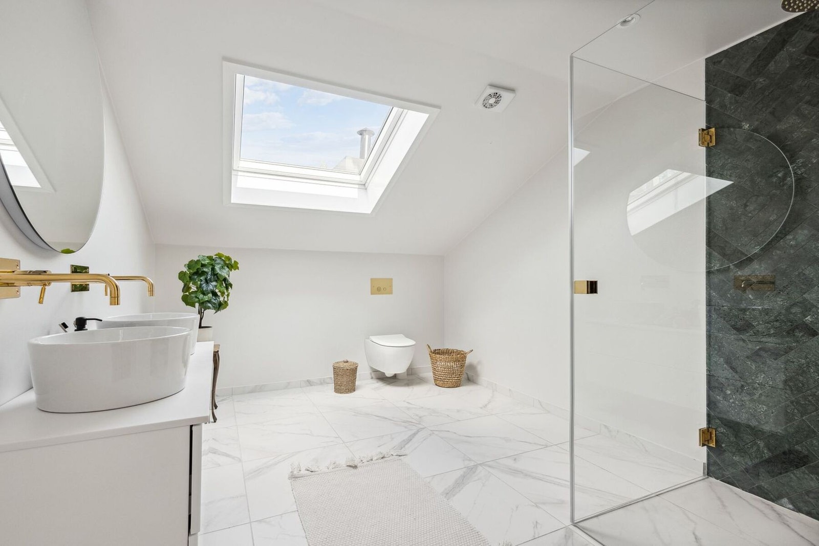 Badet er utstyrt med dusjhjørne med innfellbare glassvegger og regndusj, vegghengt wc og dobbel servantinnredning med skuffer Galleribilde