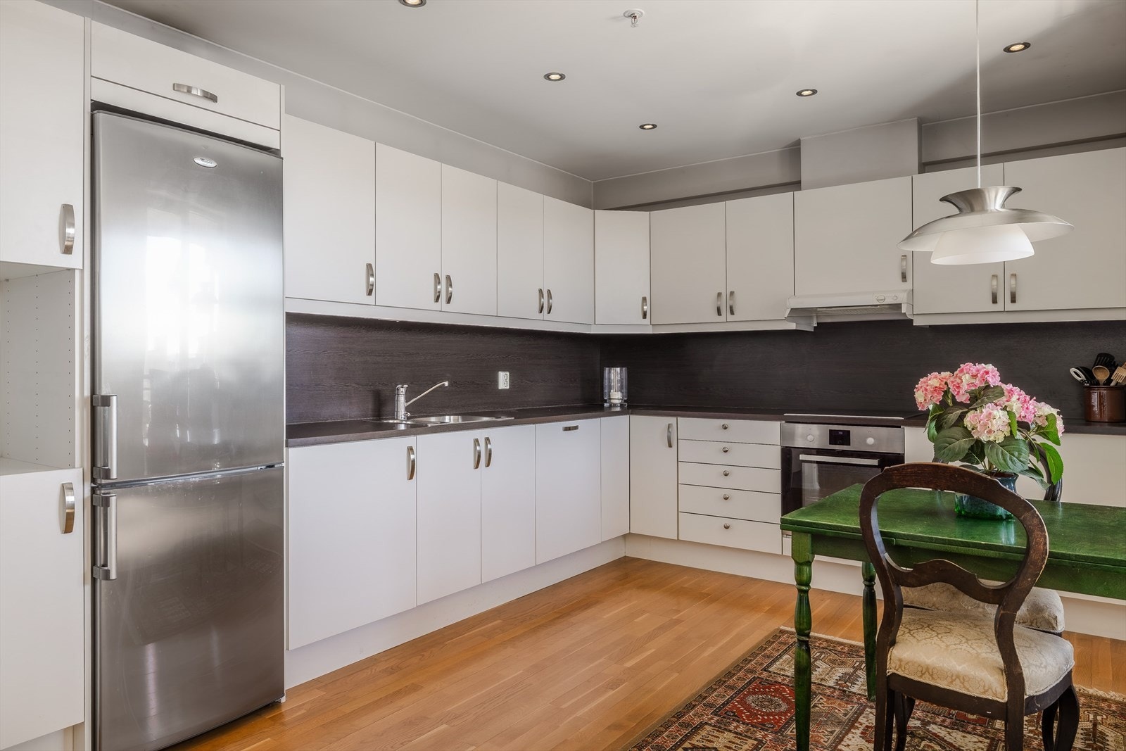 Det har hvite glatte fronter og benkeplate av laminat med nedfelt oppvaskkum i rustfritt stål med liten skyllekum. Galleribilde
