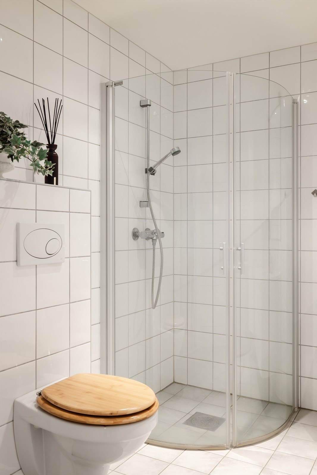 Det er utstyrt med veggmontert toalett og dusjhjørne med innfellbare glassvegger og vegghengt dusjarmatur. Galleribilde