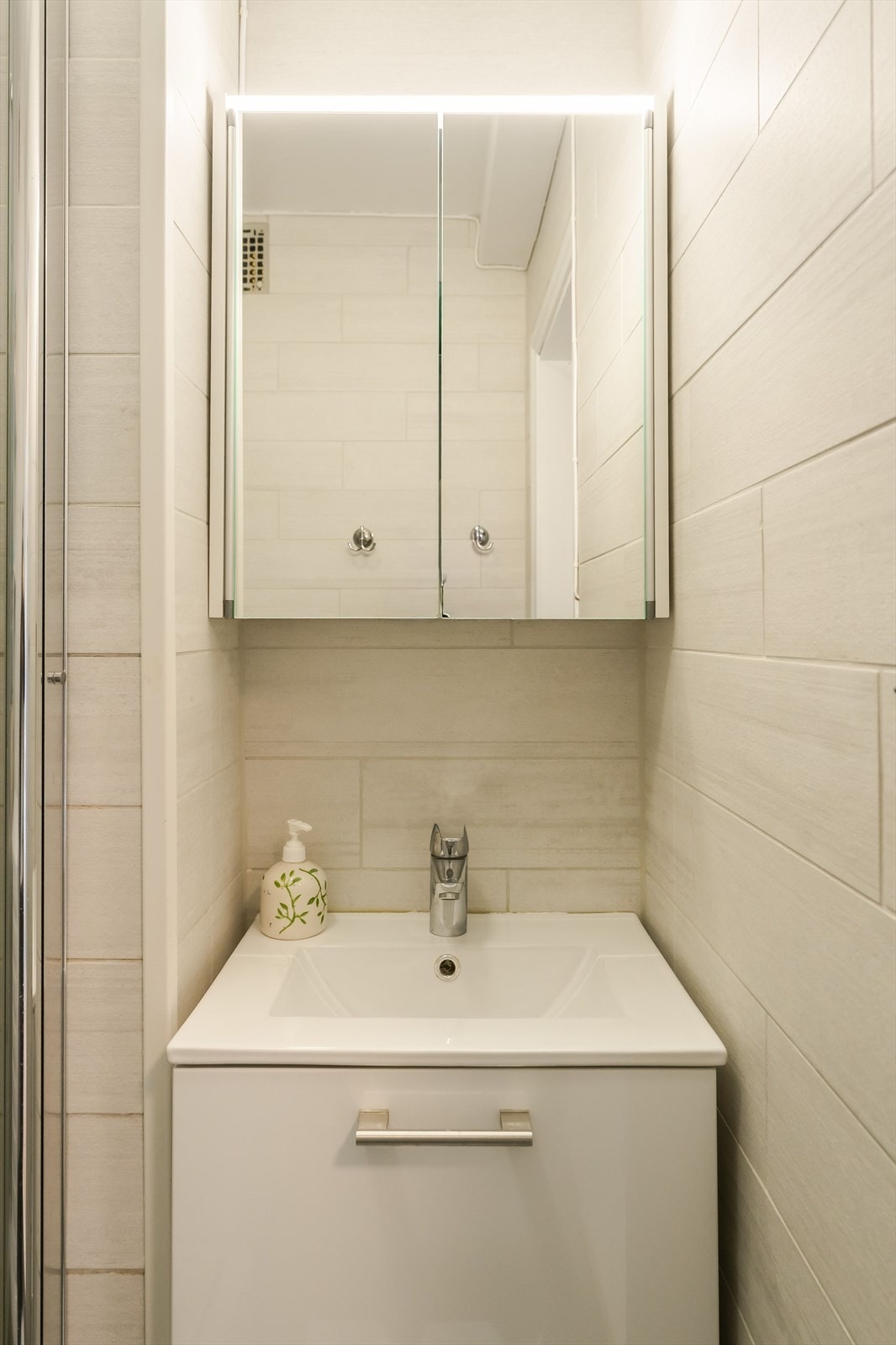 Badet fremstår som moderne, med pene overflater og belysning integrert over speil. Galleribilde