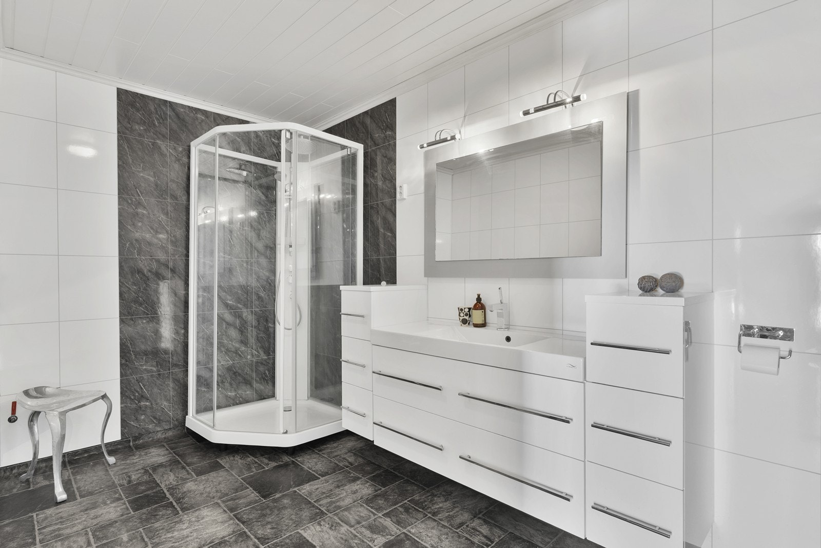 Badet har en pen baderomsinnredning med nedsenket servant, ettgreps blandebatteri, vegghengt toalett og dusjkabinett. Galleribilde