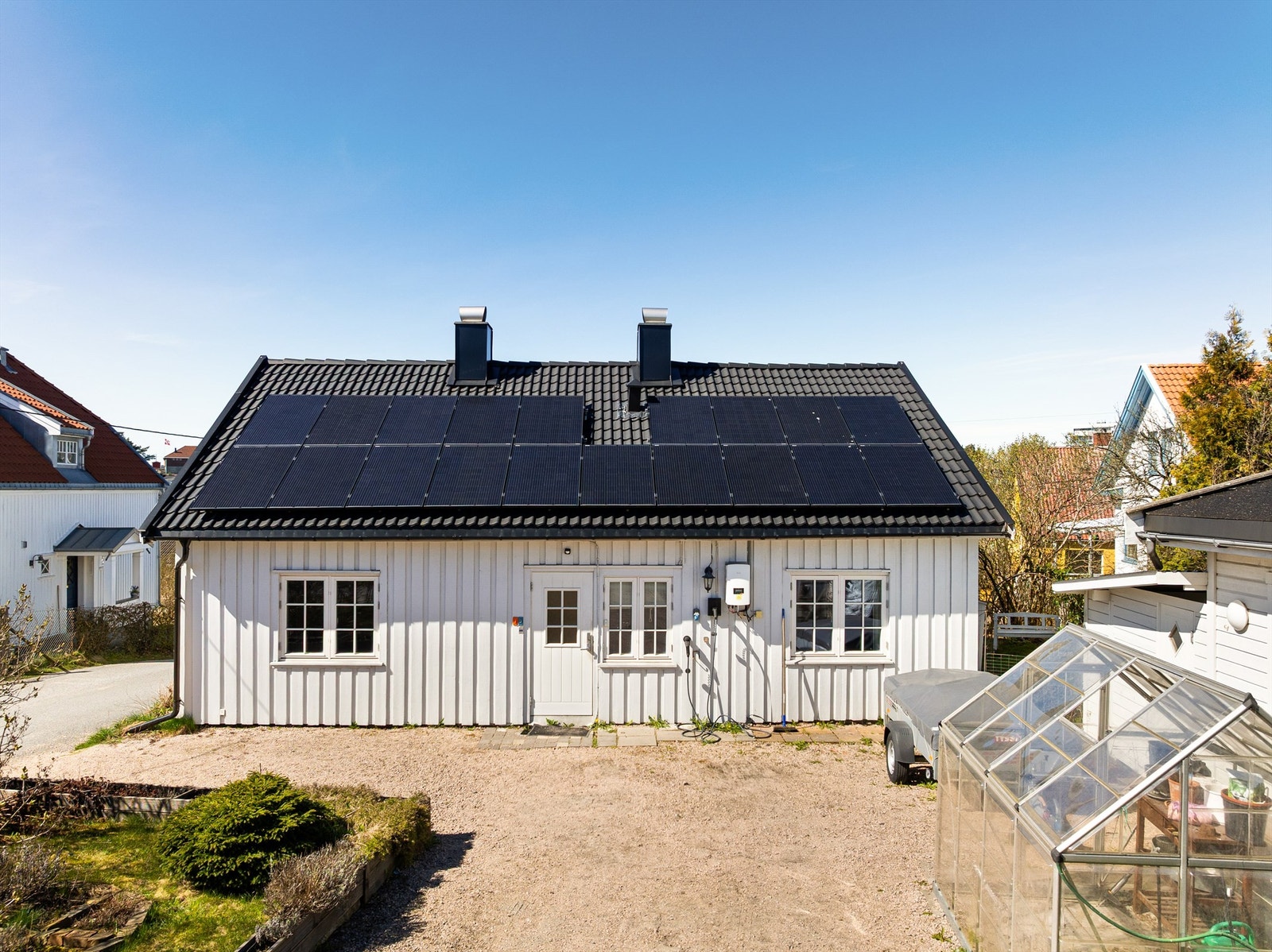 Ny, gruset gårdsplass med grønn øy ble anlagt i 2013. Lader til EL-bil er montert på husveggen. Galleribilde
